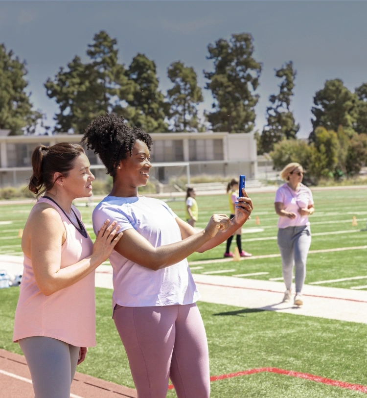 Actor portrayal of a woman who takes MYFEMBREE® (relugolix, estradiol, and norethindrone acetate) tablets taking pictures of her daughters at soccer practice